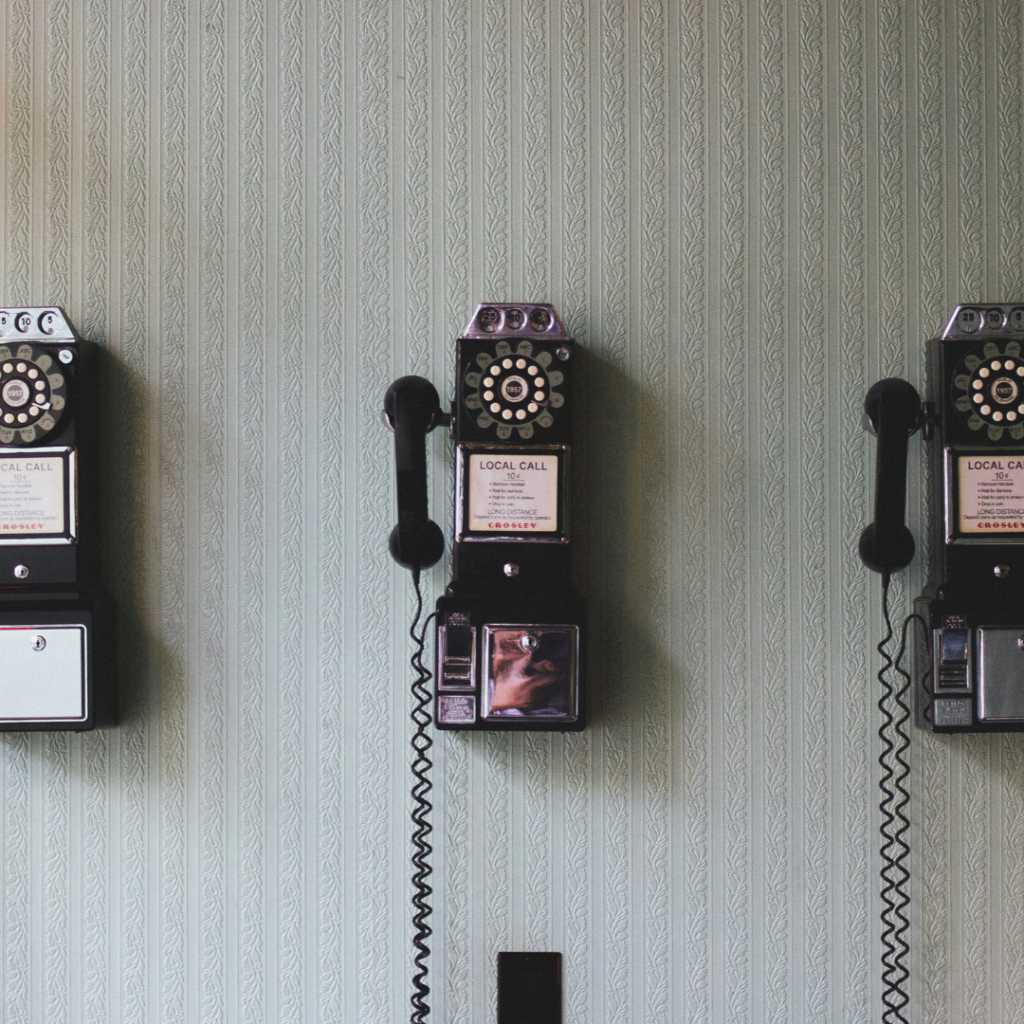 Three old black pay phones on the wall.
