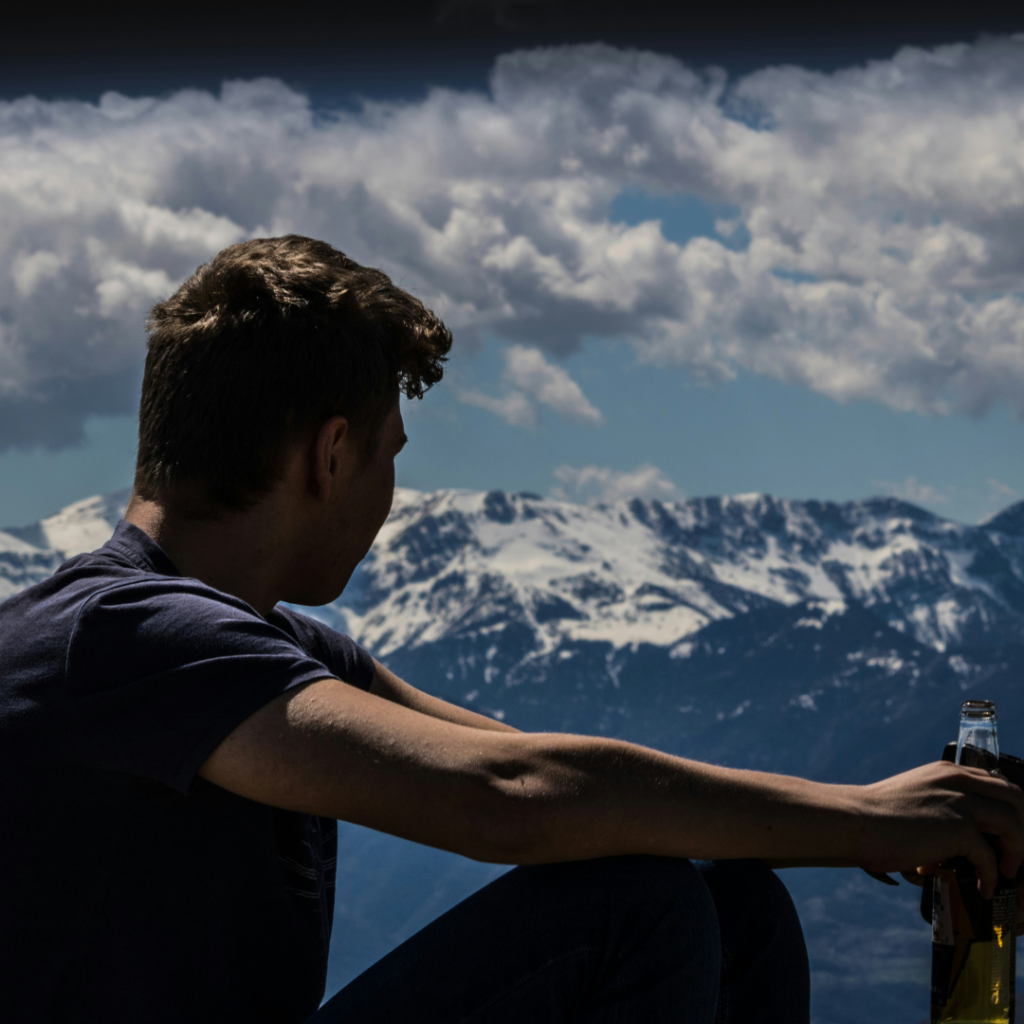 Man looking at a mountain range, looking away the world after criticism.