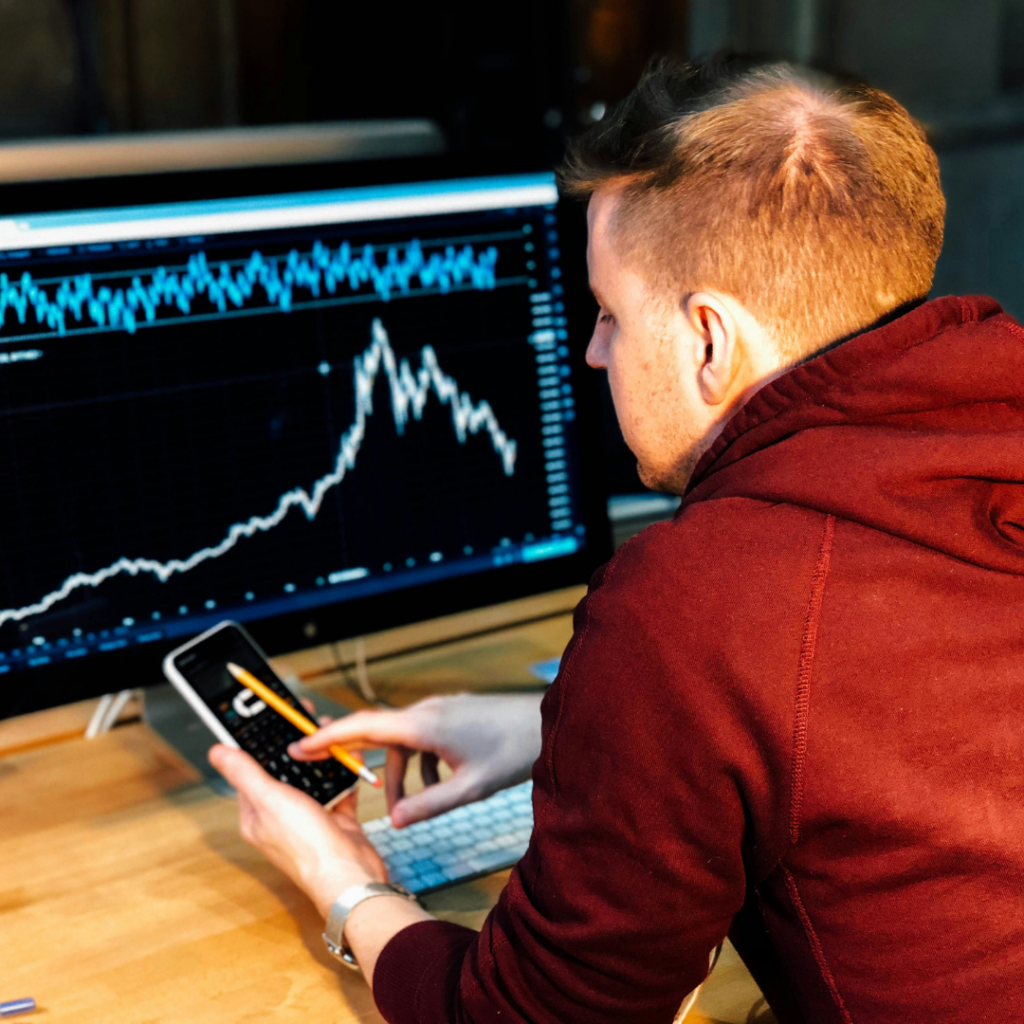 Man shown looking at charts and working on his phone, analyzing the market. Figuring out when to buy.