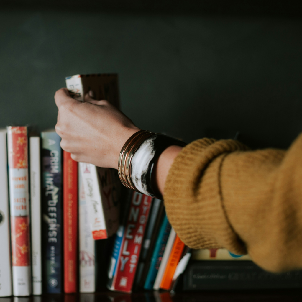 A person talking a book from a bookshelf.