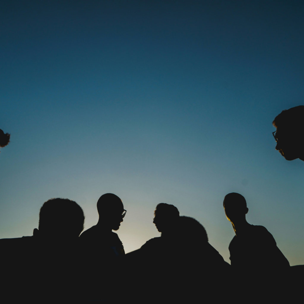 A group of men in the dusk, talking to each other.