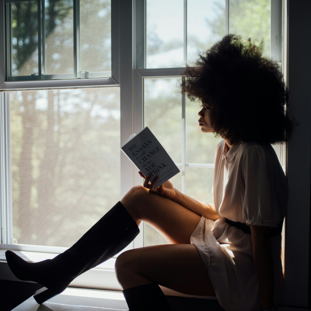 Woman reading on a windowsil by herself. Taking a moment to be alone.