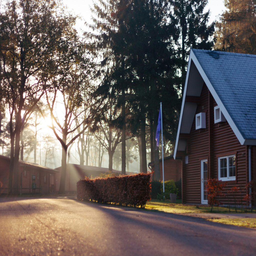 House in the woods with the sun shining through the trees.
