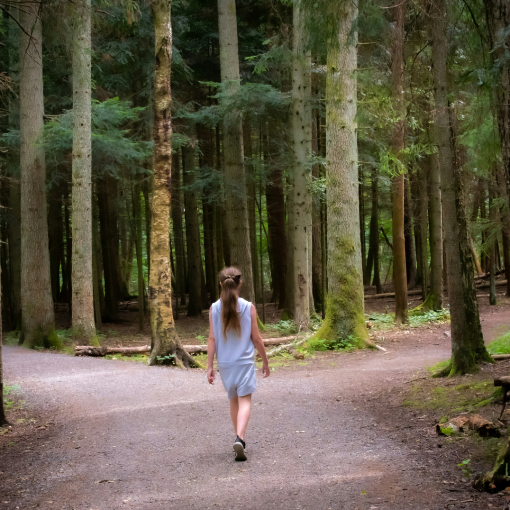 Woman walking in a forest encountering two paths.