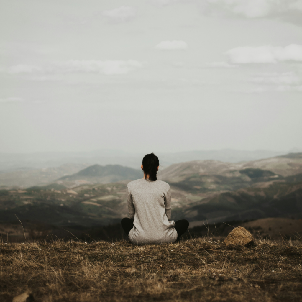 Woman reflecting like a Stoic in a mountain range.