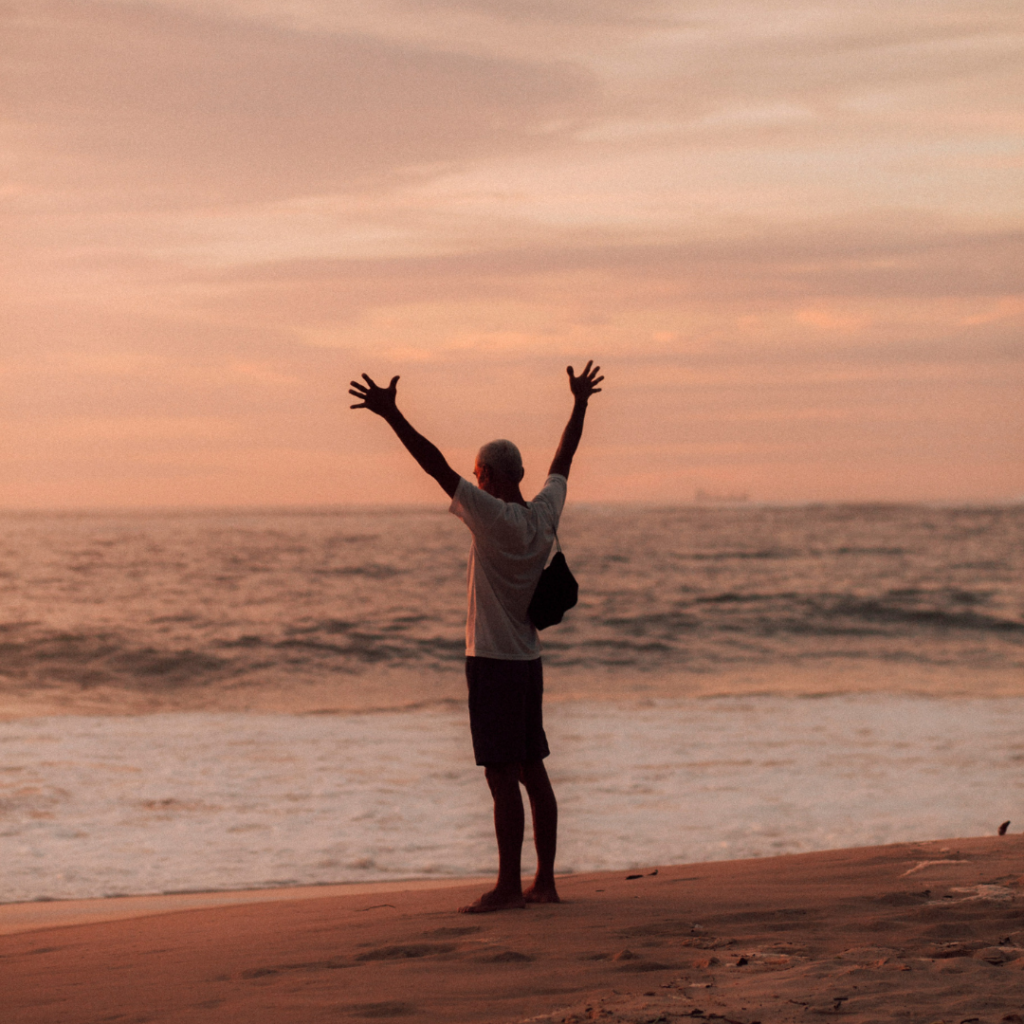 Man standing with his hands in the air out of gratitude.