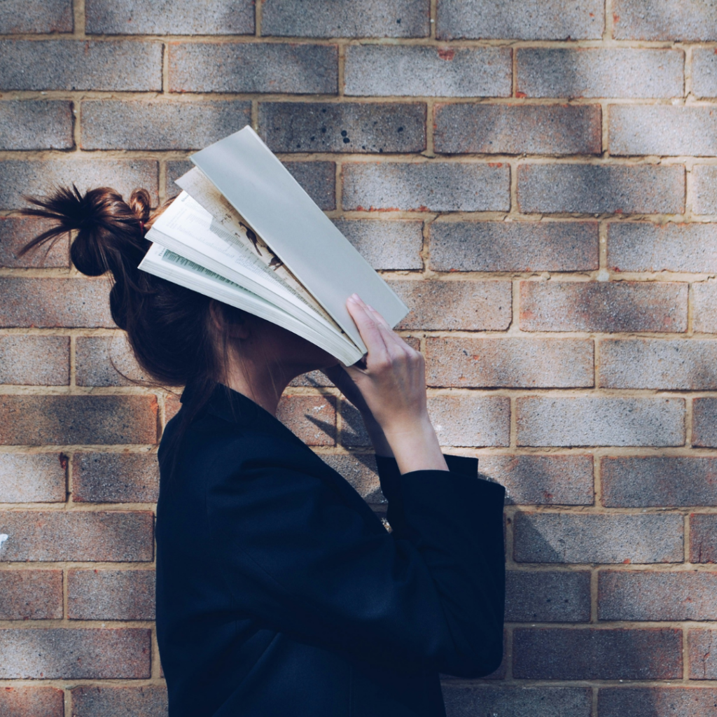 Woman covering her head with books to protect herself.