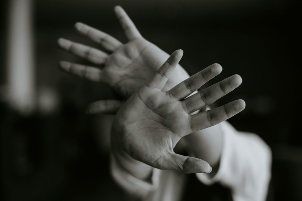 Hands of a child with their palms open to protect themselves.