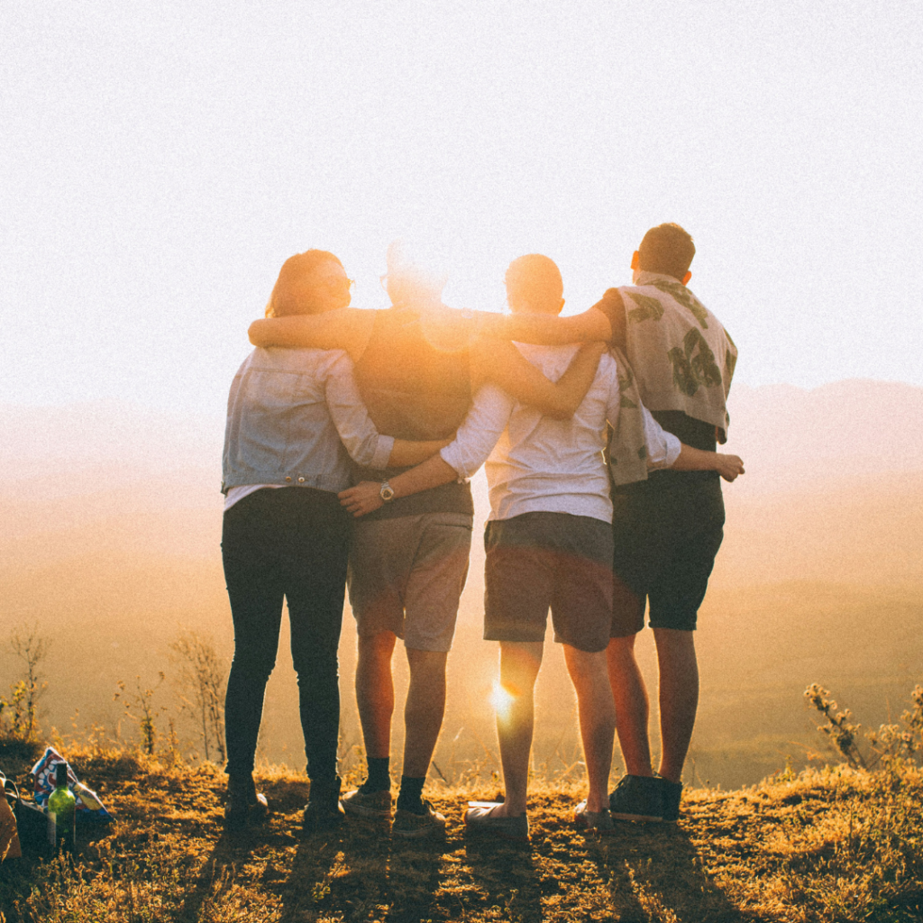 Four friends embraced looking at the sunset.