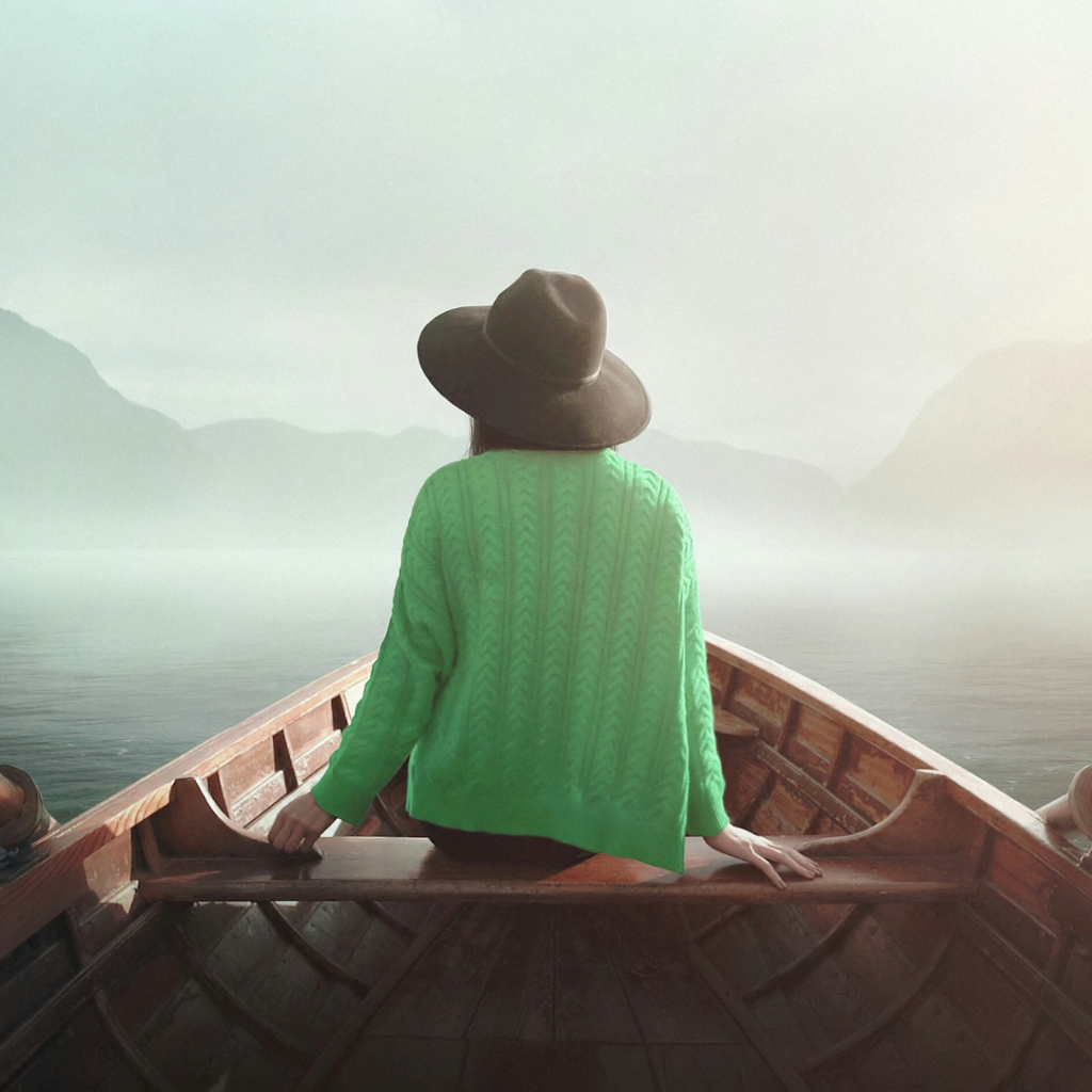 A women sitting by herself, alone, in the front of a canoe.