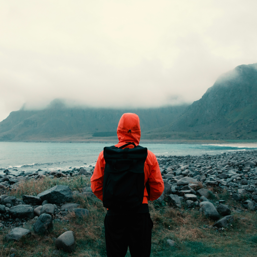 A person walking in the rain, dealing with things while traveling.