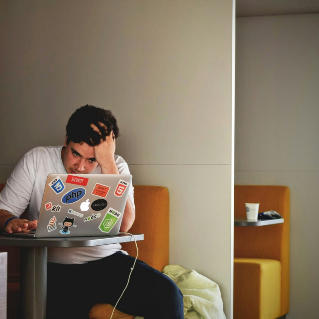 A man stressed at his wok, staring at his laptop.