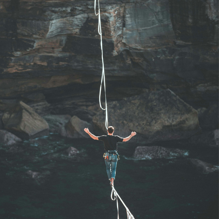 A man balancing on a tight rope over a canyon.